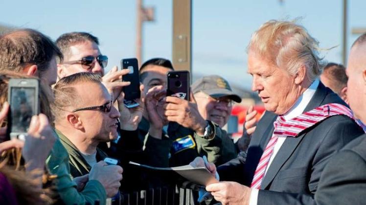US-Präsident Donald Trump (r.) gibt am 26.01.2017 bei der Ankunft auf der Andrews Air Force Base einem Senior Master Sergeant ein Autogramm. 