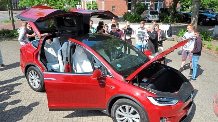 Blickfang: Der feuerrote Tesla „Model X“ zog am Montag vor dem Rathaus in Dörpen mehrere Schüler in den Bann. 