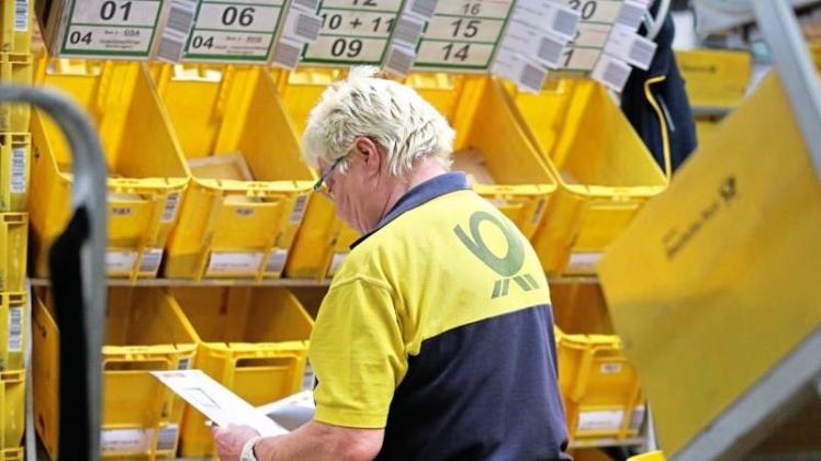 Eine ältere Post-Mitarbeiterin sortiert Briefe im Briefzentrum Leipzig. 