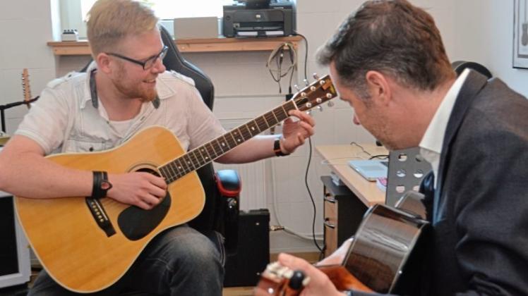 Musiklehrer Jan Frerichs bringt Besucher Christian Dürr einen Akkord auf der Gitarre bei. 