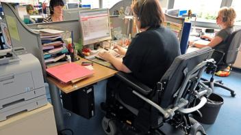 Eine im Rollstuhl sitzende Frau arbeitet als Telefonserviceberaterin im Servicecenter. 