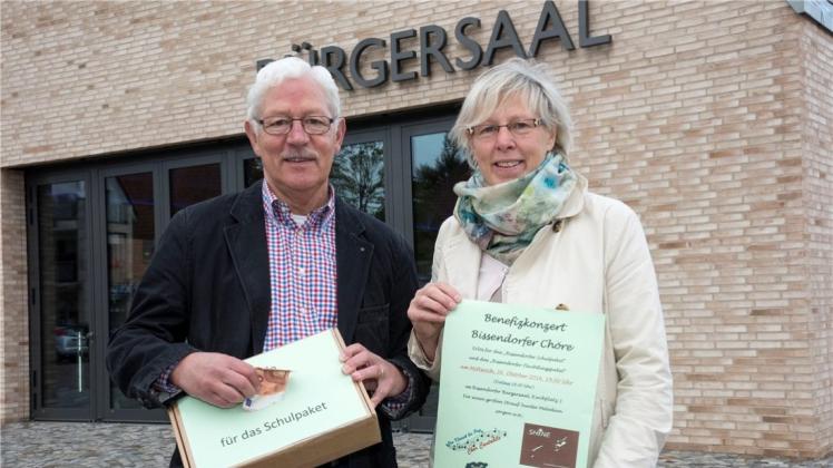 Voller Vorfreude: Mit Werbeplakat und Spendenpaket in der Hand stehen Wilfried Langhans und Doris Beinker vor dem Veranstaltungsort des Benefizkonzertes. 