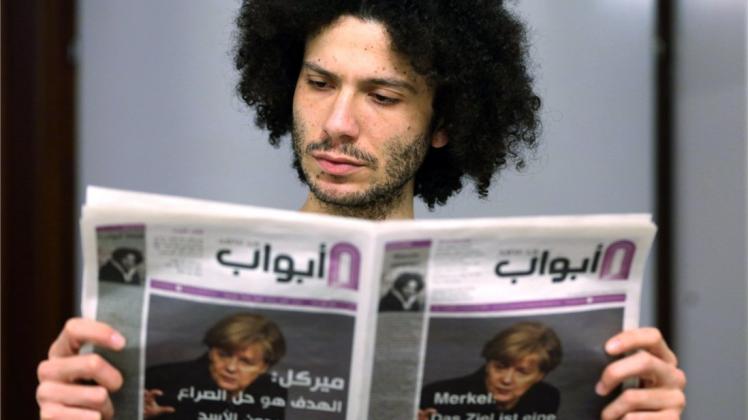 Der syrische Flüchtling Ramy Al-Asheq, Chefredakteur der Flüchtlingszeitung „Abwab“, hält eine Ausgabe der Zeitung in der Hand. 