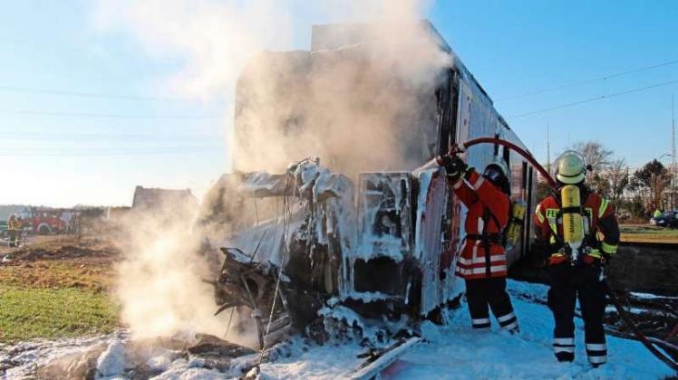 Feuerwehrleute löschen in Landesbergen den brennenden Führerstand eines Regionalzuges. Der Zug war mit einem Müllwagen zusammen gestoßen. 