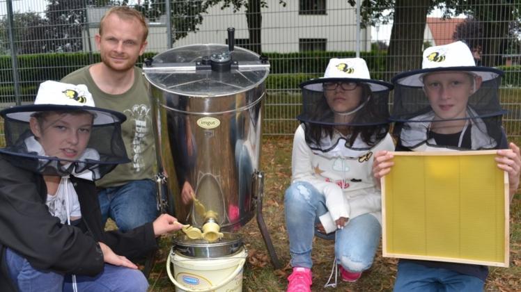 Biolehrer Philipp Schünemann und seine Schüler (v. l.) Paul, Pongsi und Pierre haben mit einer Schleuder Honig vom neuen Schulbienenvolk geerntet. 