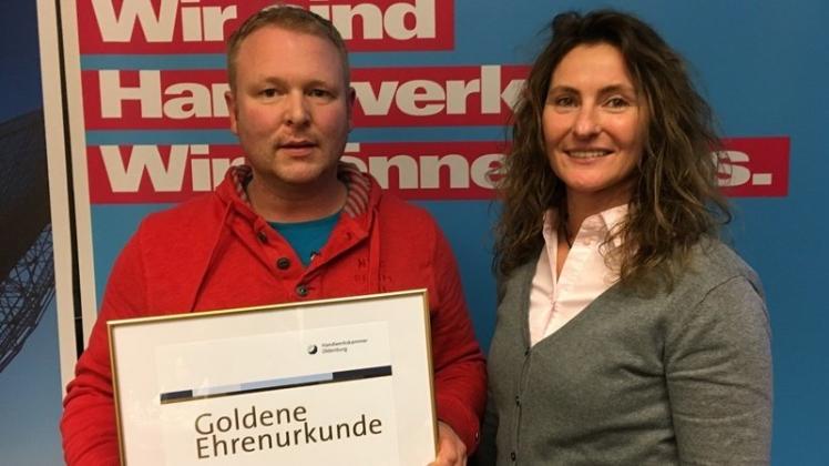 Fleischermeister Andreas Tonn nimmt die Goldene Ehrenurkunde der Kreishandwerkerschaft von Kreishandwerksmeisterin Britta Jochims entgegen. 