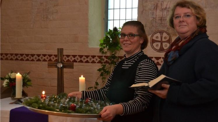 Die Kirchenälteste Rike Hollmann (links) und Pastorin Uta Brahms kündigen besinnliche Kurzandachten zur Adventszeit in der Sakristei der Sankt-Cyprian-und-Cornelius-Kirche an. 