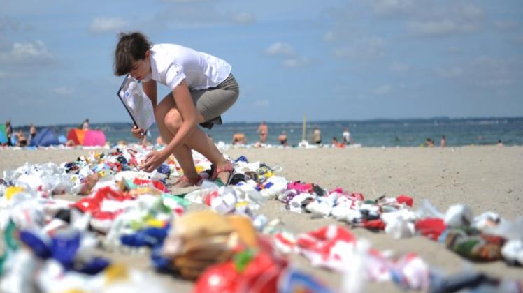 Mehr als 5000 gebrauchte Plastiktüten liegen am Strand von Niendorf (Schleswig-Holstein). Zusammengeknotet bilden sie einen Fisch. Mit diesem Guinness-Rekord für die längste Plastiktütenkette der Welt wurde 2013 auf auf die wachsende Menge von Plastikmüll in den Meeren aufmerksam gemacht. Foto: Angelika Warmuth/dpa