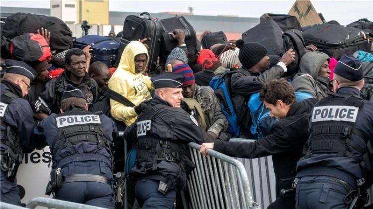 Ein starkes Polizeiaufgebot begleitete am Montag Hunderte von Menschen, die die Flüchtlingscamps bei Calais verließen. 