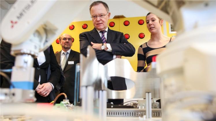 Ministerpräsident Stephan Weil ließ sich von Mechatronik-Auszubildende Nicole Schwarz (Volkswagen Osnabrück) eine Robotik-Anlage zum Sortieren von Bauteilen erklären. 