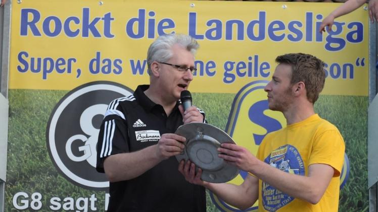 Lobt die Vereine: Frank Schulte (links), Staffelleiter der Fußball-Bezirksliga Weser-Ems 2, der hier Daniel von Seggern, Mannschaftskapitän des SV Atlas, die Meisterschale überreicht.  
