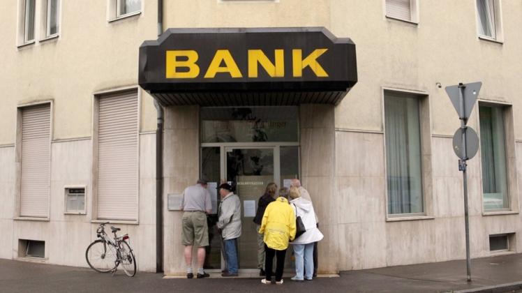 Kunden vor einer geschlossenen Bankfiliale. 