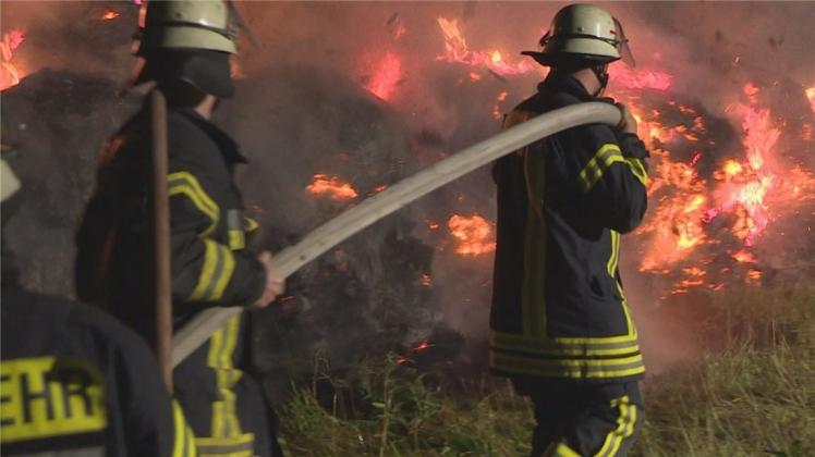 Zwei Feuerwehrleute bei den Löscharbeiten am frühen Samstagmorgen beim Heuballenbrand in Hasbergen 