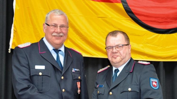 Regierungsbrandmeister Frank Knöpker (rechts) zeichnet Christoph Wessing mit dem silbernen Feuerwehrehrenzeichen am Bande für besondere Verdienste aus. 