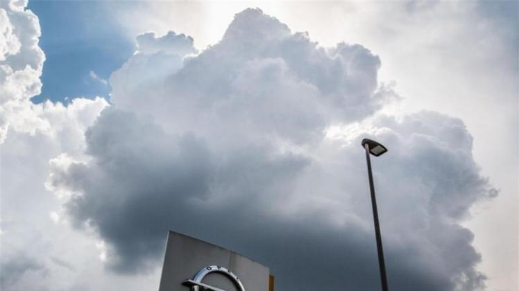 Eine einzelne dunkle Wolke schwebt in Rüsselsheim über einem Firmenlogo am Stammsitz von Opel. 