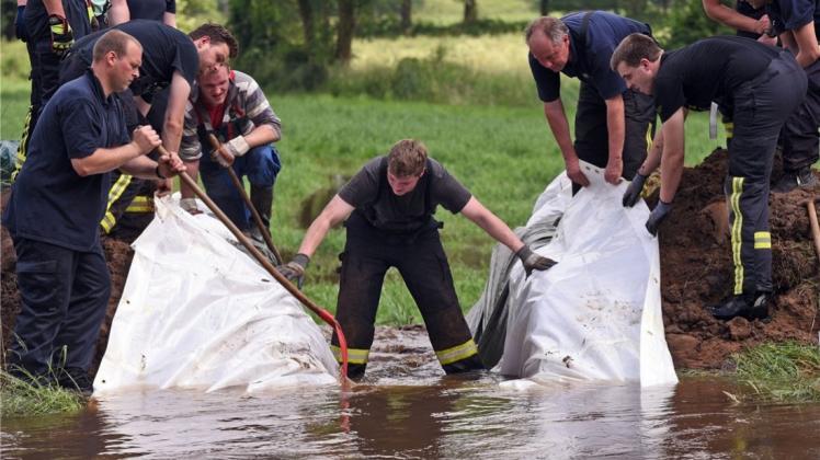 Helfer graben in Hamminkeln (Nordrhein-Westfalen) einen Durchstich in den Deich der Issel, um den Pegel zu senken. Nach starken Regenfällen ist der sonst kleine Fluss stark angeschwollen. Henning Kaiser/dpa
