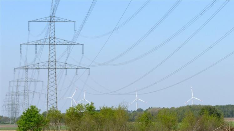 Eine mächtige Stromtrasse verläuft bereits durch Teile des Bramscher Stadtgebietes. Diese Masten stehen in der Nähe der Ueffelner Straße (L70). Im Hintergrund: die Räder eines Windparks im benachbarten Merzen.