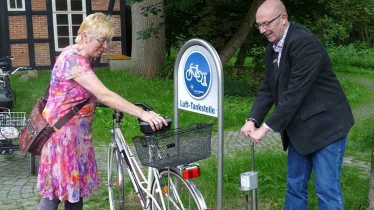 Initiator Hans-Heinrich Kellner demonstriert die neue Luft-Tankstelle in Heiligenrode und pumpt für Radfahrerin Iris Rose den Reifen auf. 