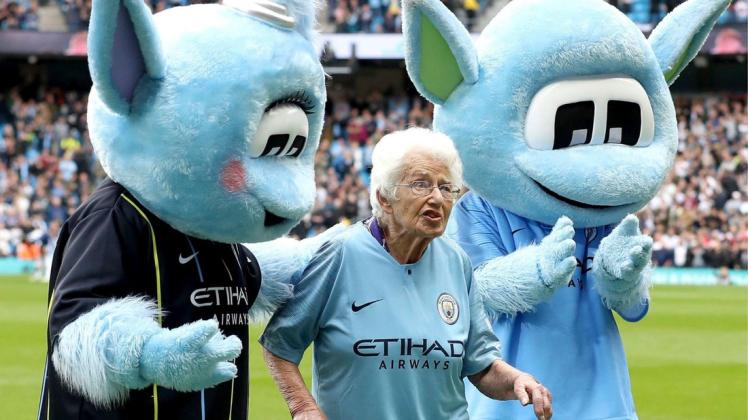 Die beiden City-Maskottchen Moonchester (r) und Moonbeam stehen vor dem Spiel mit der 102 Jahre alten Vera Cohen am Spielfeldrand.