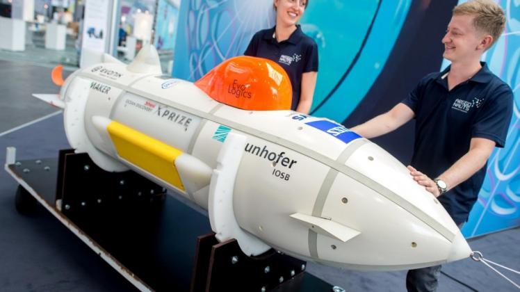 Sarah Wieners und Christopher Wetzel, beide wissenschaftliche Mitarbeiter der Fraunhofer-Gesellschaft, stehen neben einem autonomen Unterwasserfahrzeug, mit dem der Meeresboden kartiert werden kann. Foto: dpa