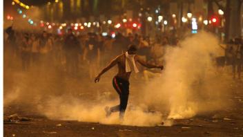 Ein Mann tritt eine von der Polizei geworfene Tränengasgranate während Ausschreitungen auf der Champs Elysees in Paris nach dem WM-Gewinn der Franzosen. Foto: picture alliance/dpa