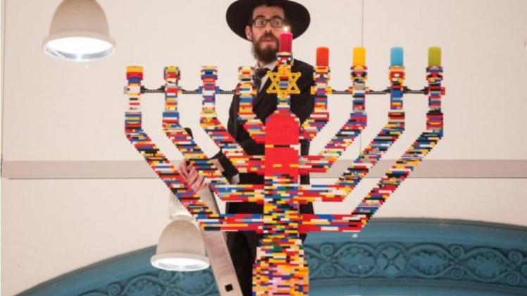 Auf einer Leiter stehend hat der Rabbiner Shmuel Havlin Joseph-Carlebach-Schule Kerzen eines Chanukka-Leuchters aus Legosteinen angezündet. 