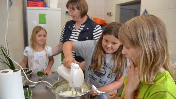 Maris Aileen Loewenstein, Talia Drieling, Landfrau Annelene Meyer und Lynn Thiede (von rechts) bereiten 2015 den Gänseblümchen-Kräuterquark bei der Ferienspaßaktion Kinderkochen mit den Landfrauen. 