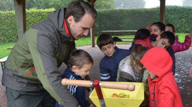 Beim Feriensprachcamp des Regionalen Umweltzentrums Hollen (RUZ) presst Etienne Sandau, Lehramtsstudent in Vechta, mit den Kindern Äpfel zu Saft. 