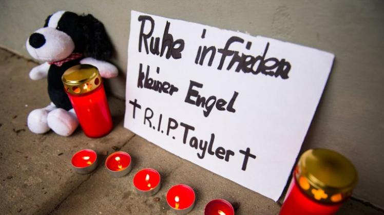 Ein Schild mit der Aufschrift „Ruhe in Frieden kleiner Engel. R.I.P. Tayler“, Kerzen und Plüschtiere stehen in Hamburg vor einem Wohnblock im Stadtteil Altona-Nord. 