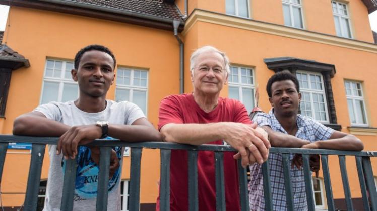 Der Bundestagsabgeordnete Martin Patzelt (M, CDU) und die beiden Flüchtlinge aus Eritrea Haben (l, 19) und Awet (r, 24) am Zaun des Gemeinde- und Vereinshauses des kleinen Ortes Briesen. 