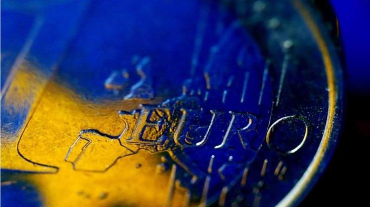 Die Fahne der Europäischen Union (EU) spiegelt sich in einer Euro-Münze. 