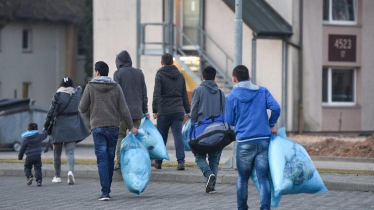 Flüchtlinge, die sich mit ihren Kleidersäcken auf den Weg zur Erstaufnahmeeinrichtung in Heidelberg machen. 
