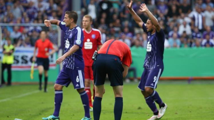 Der bittere Moment: Schiedsrichter Martin Petersen krümmt sich, nachdem er von einem Feuerzeug getroffen wurde, die VfLer Alexander Dercho (l.) und Halil Savran wollen die Fans beruhigen. Der bittere Moment: Schiedsrichter Martin Petersen krümmt sich, nachdem er von einem Feuerzeug getroffen wurde, die VfLer Alexander Dercho (l.) und Halil Savran wollen die Fans beruhigen.