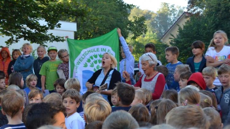 Ute Aschemann und Karin Rohde singen mit den Kindern, die die Flagge bereits in den Händen halten. 