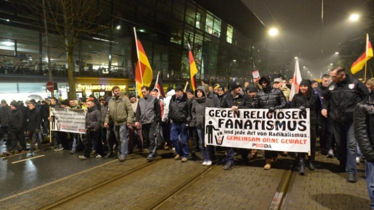 Teilnehmer der Pegida-Bewegung ziehen mit Transparenten und Fahnen bei einer Kundgebung in Dresden am Stadion des Fußball-Drittligisten Dynamo Dresden vorbei. 
