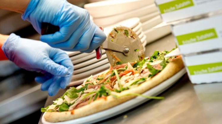 Ein Mitarbeiter von Joey’s Pizzaservice schneidet eine Pizza. 