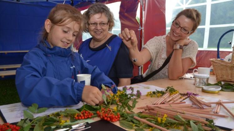 Bettina Janßen (Mitte) erklärt Amy (links) und Silke Brischkowski, mit welchen Blüten und Früchten sie malen können. 