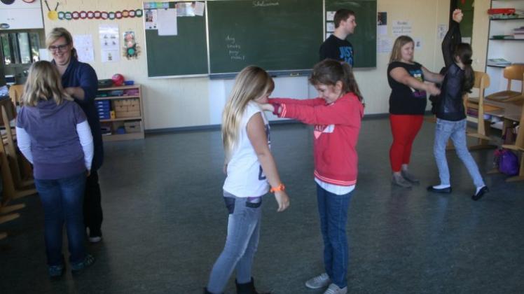 Die Teilnehmerinnen und Jutta Becker (links) üben, wie sie sich aus einem Schultergriff lösen. 