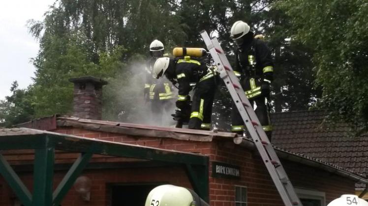 Feuerwehrleute gehen vom Dach aus gegen den Schwelbrand im Ferienhaus vor. 