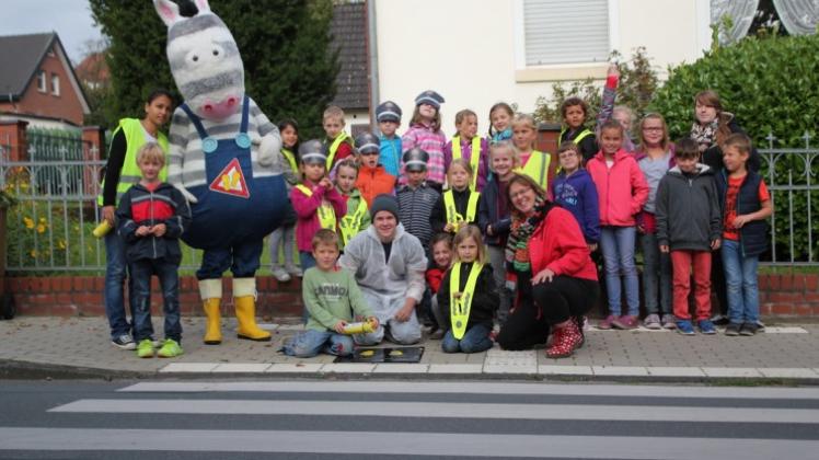 Mit Zebra am Zebrastreifen: Hasberger Kinder markieren dieser Tage wieder sichere Schulwege mit kleinen gelben Füßen. Polizist Thomas Mäster (im Kostüm) unterstützt die Aktion von Katrin Schmidt (vorne rechts). 