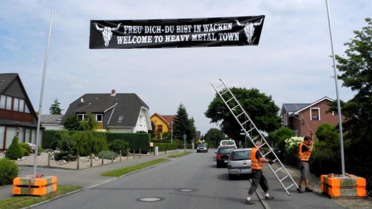 Mitarbeiter des Musikfestivals in Wacken in Schleswig-Holstein befestigen ein Banner mit dem Logo des Heavy-Metal-Festivals. Das Großereignis feiert in diesem Jahr sein 25-jähriges Bestehen. 