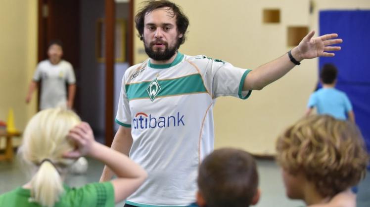 Lehramtsstudent Kristian Bunte erklärt Grundschülern während der Fußball-AG eine Übung. 