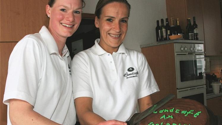 Carola Eckhoff und Sonja Ehrig freuen sich beim Anschnitt des ersten Kuchens auf ihre Gäste im neu eröffneten „Landcafé Am Goldbach“. 