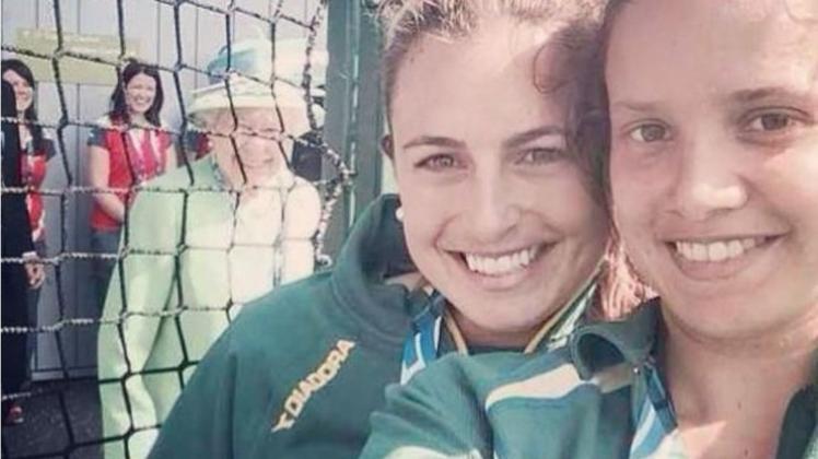 Australiens Hockeyspielerinnen Jayde Taylor (links) und Brooke Peris strahlen in die Kamera. Im Hintergrund lächelt die Queen. 