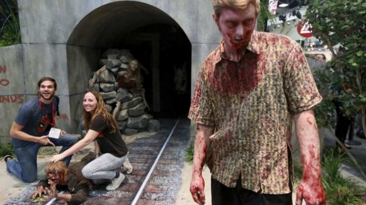 Fans der Serie „The Walking Dead“ schießen auf der Comic Con 2014 ein Foto neben einem Mann, der sich als Zombie verkleidet hat. 