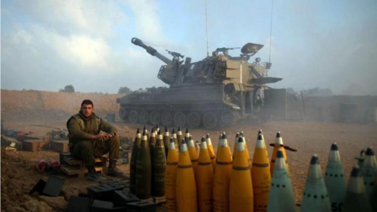 Ein israelischer Soldat sitzt unweit der Grenze zum Gazastreifen neben Artilleriegeschossen. 