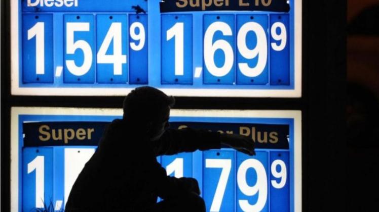 Mit Steck-Ziffern ändert ein Tankstellenmitarbeiter im April 2012 die Benzinpreise an der Anzeigentafel. 