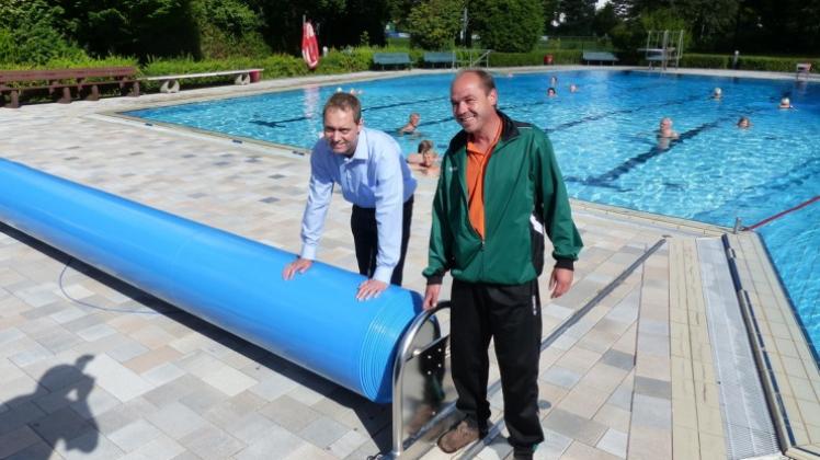 Die dreischichtige Dämmfolie, die die nächtliche Abkühlung des Freibadwassers vermindert, präsentieren Christian Elscher vom Sportamt und Schwimmmeister Volker Beinke. 