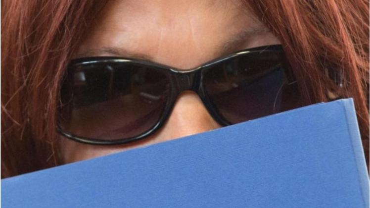 Mit einer blauen Mappe und einer Sonnenbrille verdeckt Heidi K. ihr Gesicht vor den Kameras der Fernsehteams und Fotografen. 
