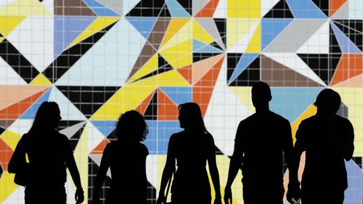 Der andere Blick auf die Kunst: Nur als Schattenrisse sind diese Jugendlichen zu erkennen, während sie in Düsseldorf vor dem aus bunten Farbflächen zusammen gefügten Wandmosaik «Hornet» der Künstlerin Sarah Morris vorbei laufen. 